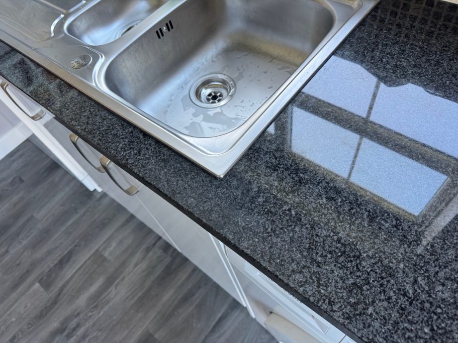 After repair: restored granite sink run Sink area all fixed at the front of the natural stone worktop. Crack was repaired with a resin and granite powder. Granite polished again.