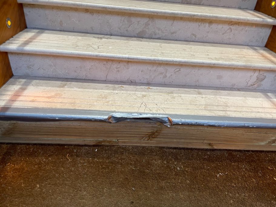 Before repair: damaged marble step front Cream marble step cracked.