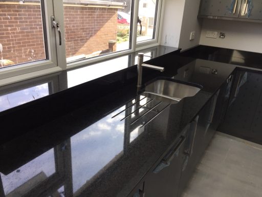 Picture showing the finished polished Work surface, the surface of the black granite needed completely repolishing. Black granite worktop with under mounted sink and draining grooves.