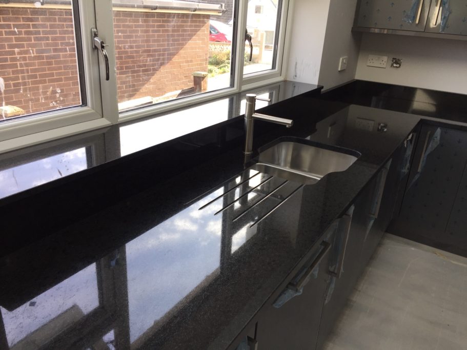 After restoration: polished black granite sink run Black granite worktop with under mounted sink and draining grooves.