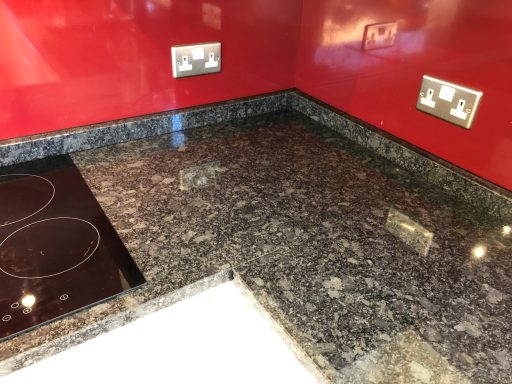 Natural granite worktop with red glass sat on the back of the upstands, with 2 cut outs for 240v sockets.  Job fitted in Sowerby Bridge.