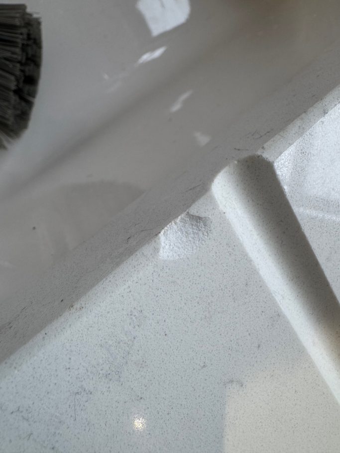 Before repair: chipped quartz beside the sink Marble effect quartz worktop chipped at the edge of the draining groove area. Dropped cup on the edge caused this damage to the quartz.