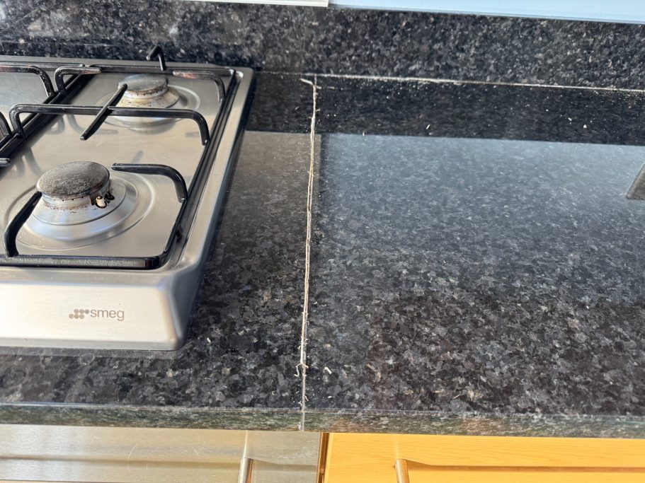 Before repair: failed granite joint seal Black granite worktop repair in west bretton near barnsley. Worktop reair needed at the joint where the old silicone had come out.