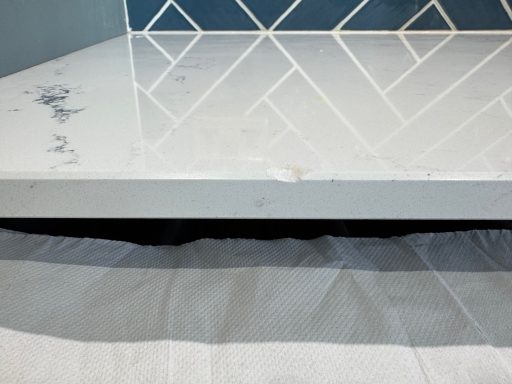 Carrera white quartz worktop with picture showing large chip out of the edge and the surface also affecting the chamfer.