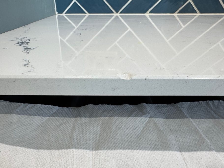 Before repair: damaged quartz chamfer White quartz worktop with damage to the chamfered edge.