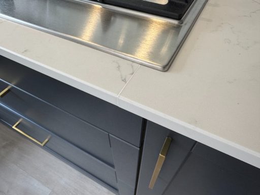 "White quartz, called Carrera White, has now been filled with resin and polished." This picture shows the joint resealed, with resin applied in the gap of the joint, making it nearly invisible.