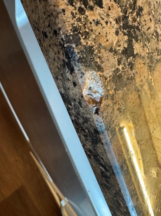 Brown granite worktop damaged with a large Chip missing from the Stone. Granite worktop in Huddersfield with surface damage to the surface and the polished edge.