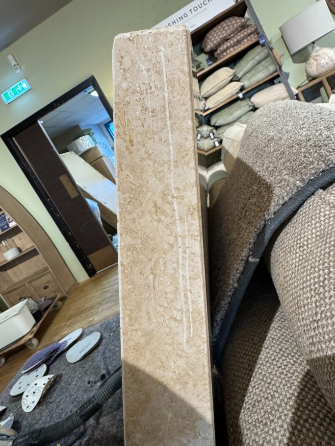 Before restoration: scratched stone table edge Stone tabletop with a scratch along its edge.