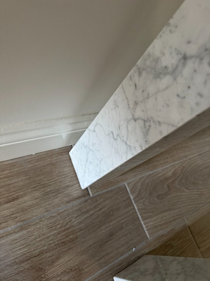 After repair: restored marble table base Close-up of a marble surface meeting a wooden floor.
