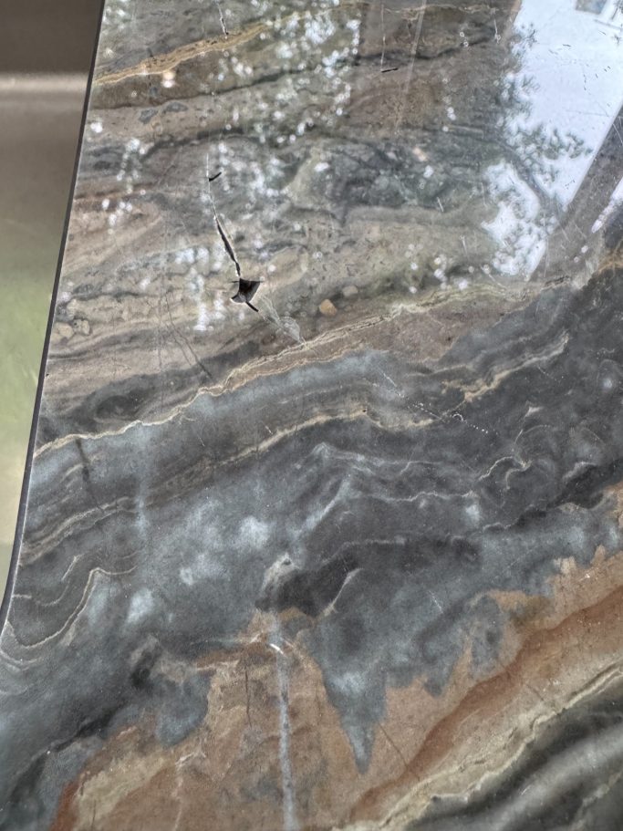 Before repair: fractured stone tabletop Fractured stone tabletop with missing sections before repair.