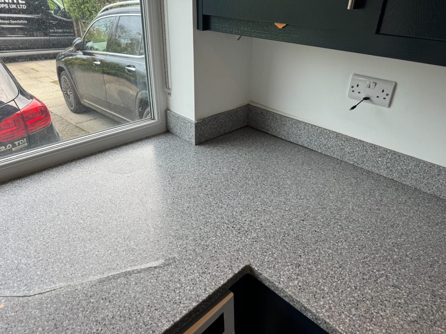 Before repair: raised crack in grey Corian Picture showing a cracked Corian worktop. The crack has lifted, causing the surface to be uneven. The crack has opened up.