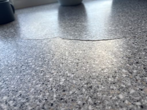 Cracked corian worktop in Leeds, West Yorkshire. Corian worktop with a large crack on the surface. The picture shows it lifted due to expansion underneath caused by moisture.