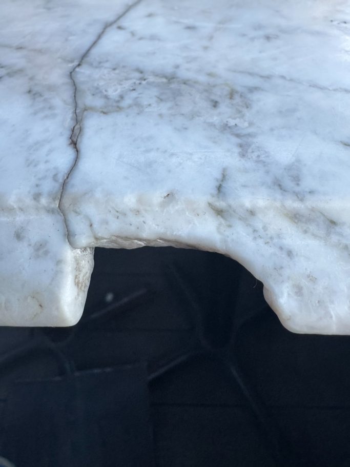 Before repair: damaged marble vanity edge White marble vanity top edge is completely smashed due to a heavy bottle of perfume that was dropped on the edge, cracking the worktop.