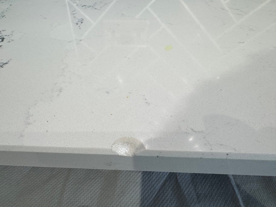 Before repair: chipped quartz edge in Penistone Carrera white quartz kitchen worktop with very large chunk missing out of the edge and surface, this job was repaired in Penistone.