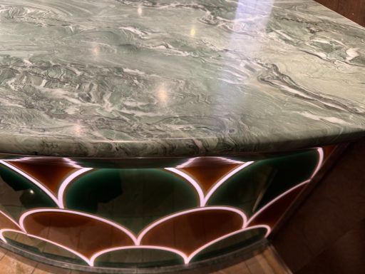 Marble tabletop with a decorative scalloped edge in green, red, and white veins. Damaged worktop in huddersfield.