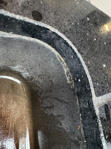 Picture showing black worktop with the silicone coming out of the Joint Sparkly black kitchen Worktop Sink area showing signs of silicone coming out of Joint this was because of its age.