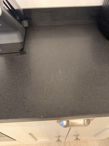 Picture of a marked kitchen worktop. The picture shows scratches from where birds have been viewed. Black honed natural granite surface scratched and marked by a heavy pan. The pan was run across the worktop, leaving the surface scratched.