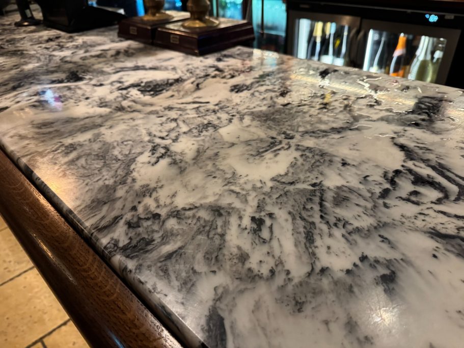 Restored public-house bar top Marbled grey and white countertop with a shiny finish. Bar area top was scratched and stained . Granite worktop was repaired in huddersfield