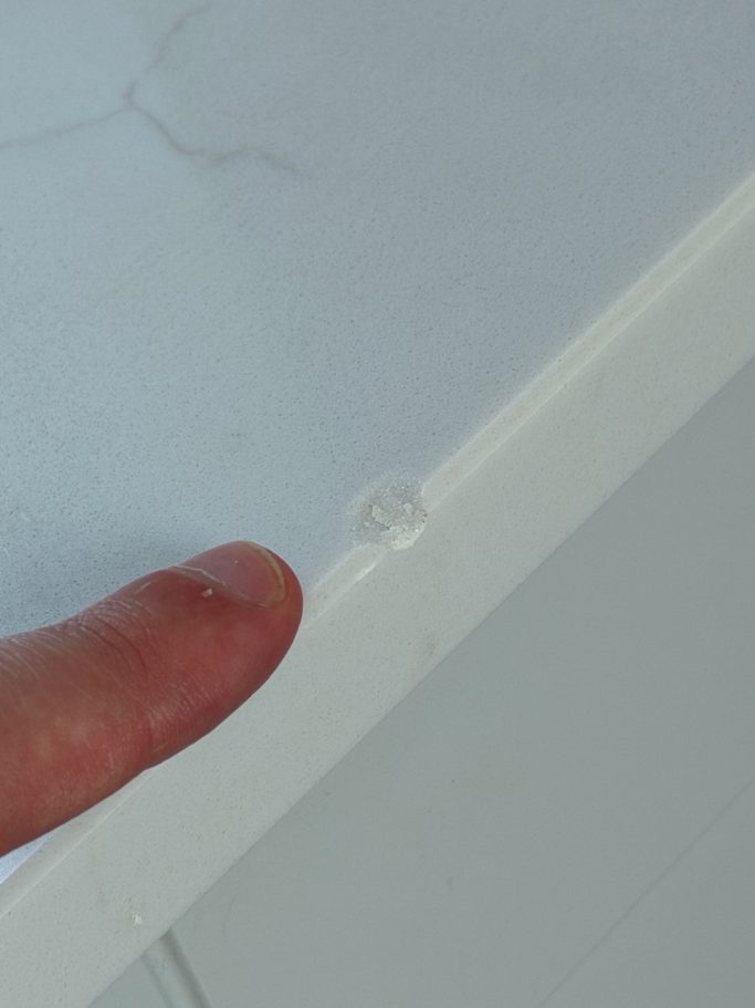 Before repair: chipped white worktop edge White worktop with a chipped polished edge before repair.