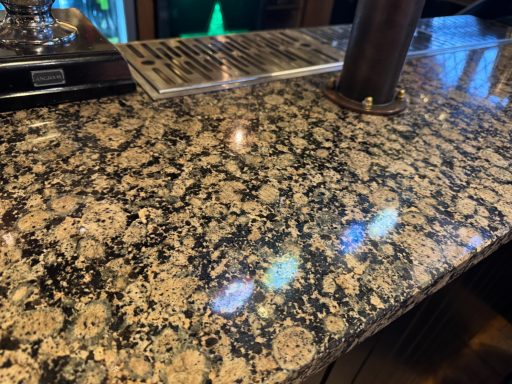 Textured granite bar top with a mixture of brown and cream colours, reflecting light. Public house was repaired in denby dale huddersfield.