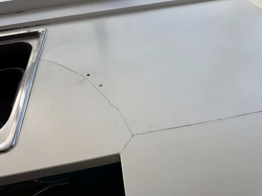 Before repair: cracked Corian beside the sink White corian repair in leeds. Joint had cracked and the worktop was also split at the side of the sink. The damaged corian was repairable.