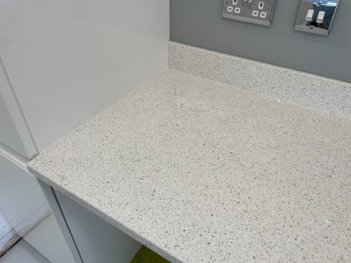 Picture of a fully restored white quartz  worktop. Worktop was lifted underneath to meet the upstand which was still glued to the wall.