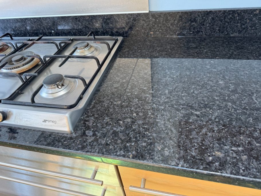 After repair: renewed black silicone joint Black granite worktop with renewed black silicone at the joint.